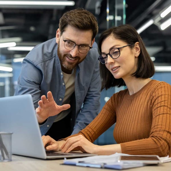 man-pointing-at-laptop-screen-woman-typing