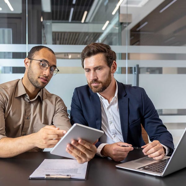 two-businessmen-reviewing-a-tablet-and-laptop